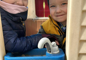 Majeczka i Bartuś w plastikowym domku na przedszkolnym placu zabaw.