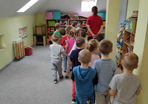 Dzieci podczas zabawy tropiącej "W poszukiwaniu pisanek", szukają śmigusówek wg wskazówek nauczycielki.