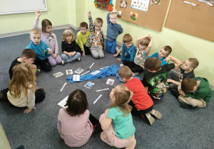 Dzieci siedzą w kole na dywanie i na podstawie obrazków nazywają faunę oraz florę rzek w Polce, jednocześnie dopasowując podpis do obrazka.