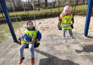 Adaś i Zuzia na huśtawkach na placu zabaw w Parku Miejskim.