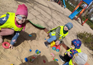 Kilkoro dzieci w piaskownicy na placu zabaw w Parku Miejskim.