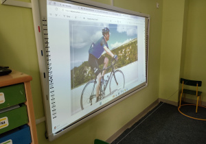 Ilustracja, przedstawiająca dyscyplinę sportową - kolarstwo na tablicy interaktywnej.