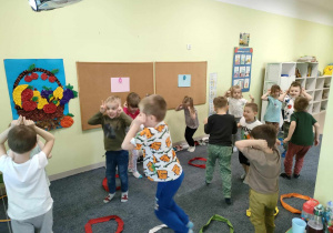 Dzieci skaczą na dywanie w trakcie zabawy ruchowej "Zajączki".