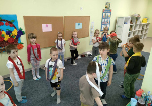 Na dźwięk trójkąta muzycznego, dzieci zakładają szarfę i stoją nieruchomo.