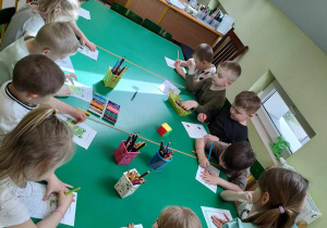 Dzieci siedzą przy stole i wykonują wybraną przez siebie wiosenną kartę pracy.