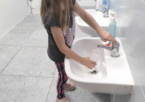 Dziewczynka z "Biedronek" nalewa czystą, świeżą wodę do poidełka.