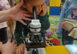 Maja korzysta z mikroskopu.