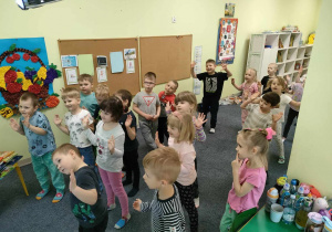 Dzieci tańczą wiosenną zumbę na boso w skarpetkach, przy wykorzystaniu tablicy interaktywnej.