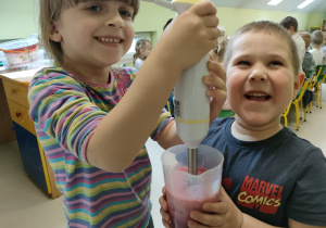 Przygotowanie zdrowej przekąski - "Wiosenne smoothie" - Karolinka i Antoś przy pomocy nauczycielki blendują wszystkie składniki.