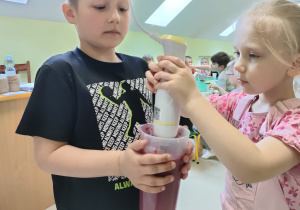 Przygotowanie zdrowej przekąski - "Wiosenne smoothie" - Alanek i Marysia przy pomocy nauczycielki blendują wszystkie składniki.