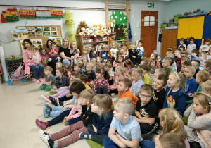 Dzieci siedzą na dywanie i słuchają wierszyka, czytanego przez p. Jacka.