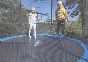 Klaudia i Filip skaczą na trampolinie.