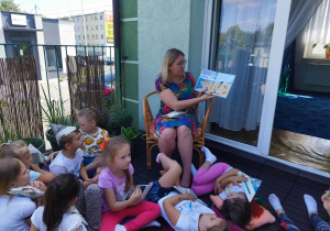 Pani Ola czyta książkę o Bolku i Lolku. Wszyscy znajdują się na tarasie biblioteki.