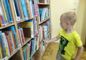 Filip rozpoznaje litery na regałach bibliotecznych.