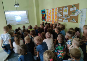 Podczas wakacji pamiętamy o nawodnieniu - najlepiej czysta woda! - dzieci starsze oglądają film edukacyjny o bezpieczeństwie podczas wakacji.