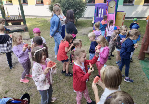 Dzieci podczas zdrowego poczęstunku na świeżym powietrzu w ogrodzie przedszkolnym.