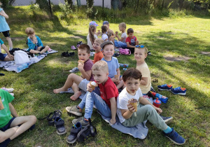 Kilkoro dzieci z "Biedronek" na kocyku, smakuje wybrane przez siebie lody.