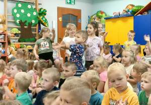 Kilkoro dzieci stoi i naśladuje ruchem p. Witka, przy akompaniamencie trąbki.