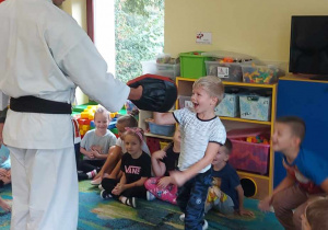 Chłopiec z grupy "Biedronek" uderza w tarczę prawą ręką. Przed nim stoi pan Łukasz z założoną na dłoń specjalną tarczą do ćwiczeń.