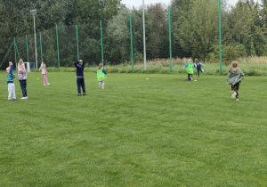 Dzieci z grupy "Pszczółek" podczas zabawy ruchowej "Berek banan" na boisku sportowym.