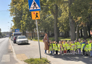 Dzieci z grupy "Żabek", ubrane w kamizelki odblaskowe podczas zajęć nt. bezpiecznego przechodzenia przez jezdnię.