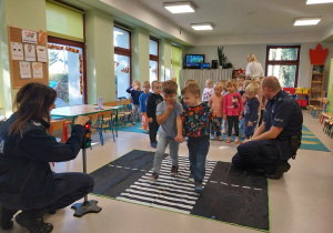 Dzieci ćwiczą prawidłowe przejście przez jezdnię.