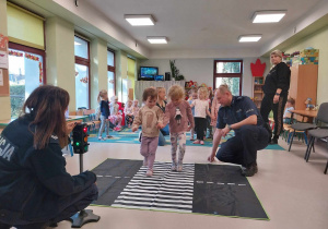 Dzieci ćwiczą prawidłowe przejście przez jezdnię.