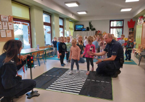 Dzieci ćwiczą prawidłowe przejście przez jezdnię.