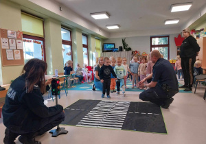 Dzieci ćwiczą prawidłowe przejście przez jezdnię.