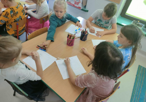 Kilkoro dzieci przy stoliku podczas rozwiązywania wybranych przez siebie zadań, opartych na ćwiczeniu logicznego myślenia i skupieniu uwagi.