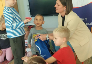 Chłopiec z "Pszczółek" losuje z woreczka i nazywa przedmiot związany z higieną skóry głowy i włosów.