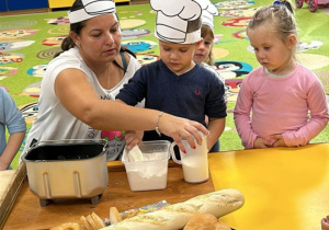 Mama Hani pomaga chłopcu przy mieszaniu mąki.