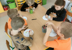 Kilkoro dzieci przy stoliku tworzy swój "talerz zdrowia".