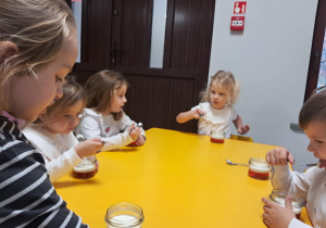 Kilkoro dzieci z grupy "Żabek" podczas degustacji deserku w barwach flagi Polski.