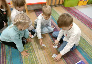 Zespół dzieci układa domino patriotyczne w jednej linii.