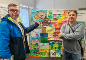 Pan burmistrz Jacek Socha wraz z radnym z Rady Miasta Ozorków p.Tomaszem Mucha pozuje do zdjęia na tle prac konkursowych. Pan burmistrz wskazuje palcem na prace wysłaną przez nasze przedszkole.