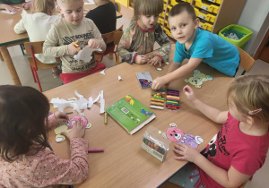 Kilkoro dzieci z grupy "Pszczółek" przy stoliku podczas misiowej pracy plastycznej.