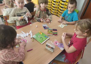 Kilkoro dzieci z grupy "Pszczółek" przy stoliku podczas misiowej pracy plastycznej.