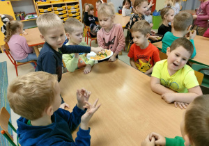 Dziewczynki częstują dzieci ich ulubionymi owocami i warzywami, które przynieśli do przedszkola.