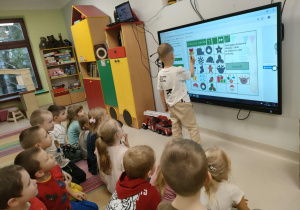 Chłopiec dopasowuje obrazek do właściwego cienia. Pozostałe dzieci siedzą, czekając na swoją kolej.