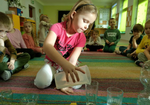 Nalewamy odmierzoną miarkę wody do przeźroczystego naczynia.