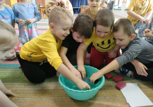 Młodsi chłopcy uczestniczą w mokrych zabawach z wodą i nasączają gąbki.