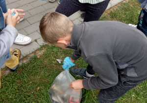 Chłopiec zawiązuje worek pełen śmieci