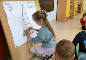 Dzieci z grupy "Pszczółek" przczepiają wybrane przez siebie piętra w odpowiednim miejscu.