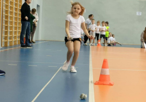 Zawodnicy podczas konkurencji sportowej - bieg po prostej do pachołka z kulką utworzoną i rzut do celu.