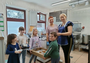 Wybrane dzieci częstują ciocie Basię oraz ciocię Anię z naszej, przedszkolnej kuchni, pysznymi, słodkimi pączkami.