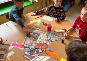 Kilkoro dzieci z grupy "Biedronek" zabiera się do pracy plastycznej, by stworzyć swojego pączka z posypką z kolorowych gazet.