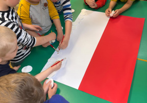 Dzieci z grupy "Motylków" wyklejają szablon flagi Polski, przy użyciu płatków kosmetycznych.