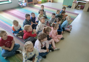 "Pszczółki" oglądają film edukacyjny nt. symboli narodowych na ekranie multimedialnym.