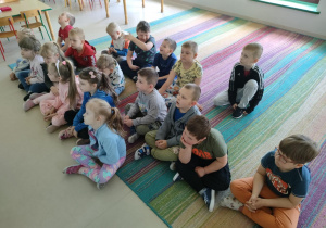 "Pszczółki" oglądają film edukacyjny nt. symboli narodowych na ekranie multimedialnym.